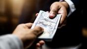 Мужчина передает пачку долларов другому мужчине